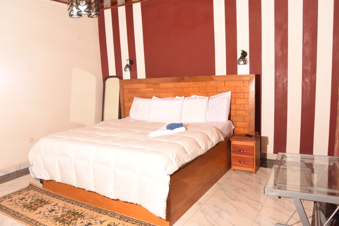 Chambre avec lit king size, tête de lit en bois et suspensions design
