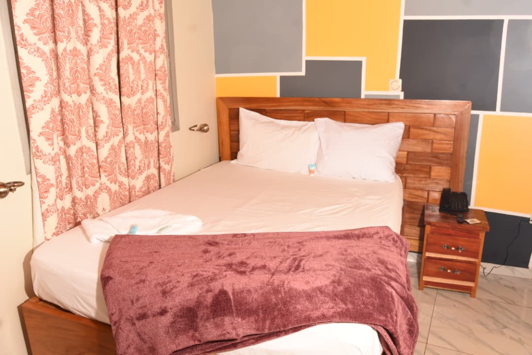 Chambre avec mur coloré jaune et gris, lit double et rideaux à motifs